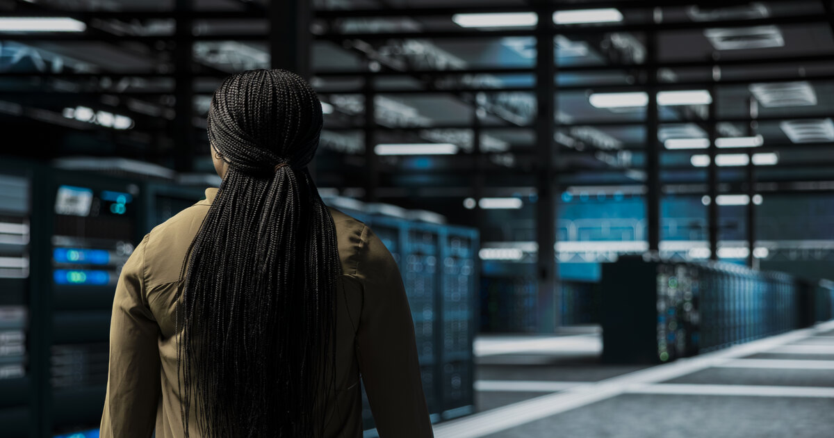 IT worker walking through a server room lined with infrastructure racks